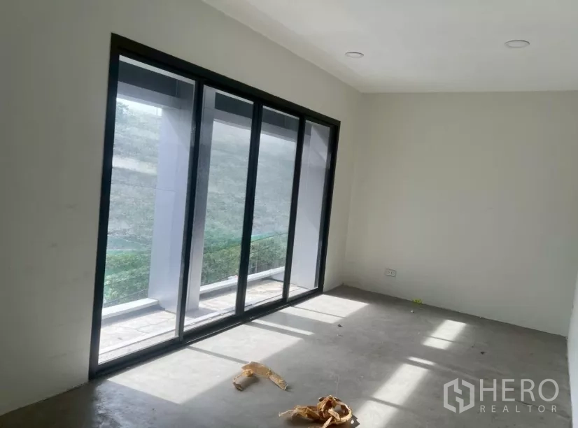 Shophouse for rent in Watthana, Bangkok - Bright upper-floor room with large sliding glass doors opening to a balcony.