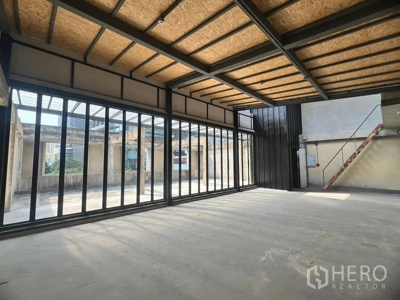 Retail Space for rent in Watthana, Bangkok - Open-plan interior with wide sliding glass doors to the terrace and exposed steel beams.