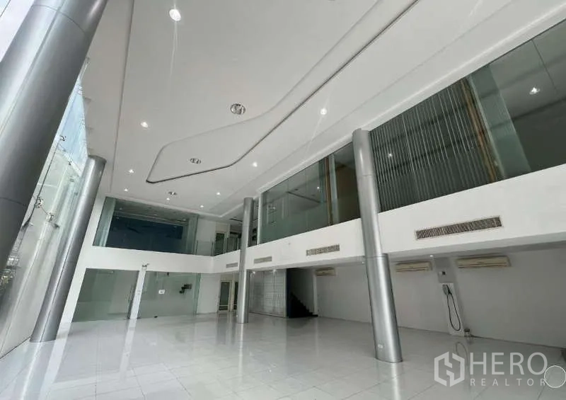 Showroom for rent - Spacious display area with white floors, tall pillars, and mezzanine walkways.