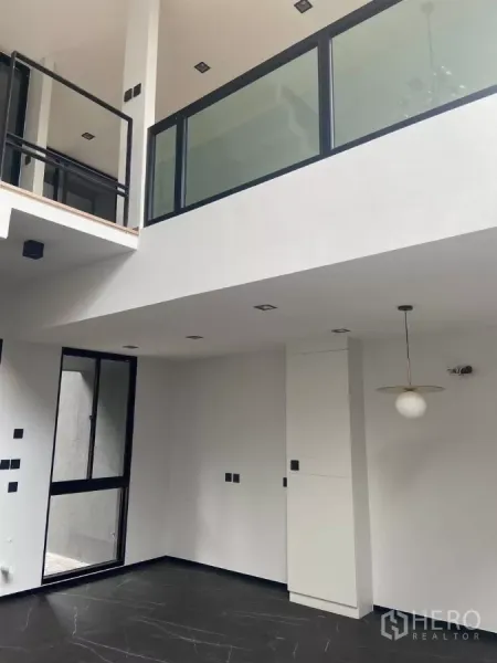 Townhouse for rent in Huai Khwang, Bangkok - Mezzanine level with glass balustrade overlooking the open-plan living space.