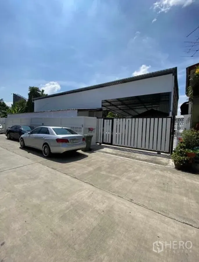 Warehouse for rent in Bang Khen, Bangkok - Street view of the gated warehouse facade with parking and a sliding metal gate.