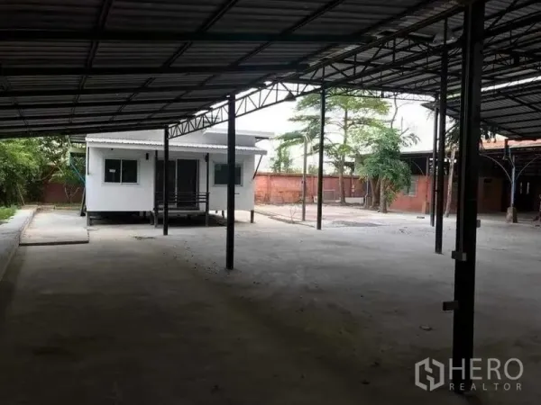 Warehouse for rent or sale in Khlong Sam Wa, Bangkok - Covered yard with a white modular office cabin beside open warehouse bays.