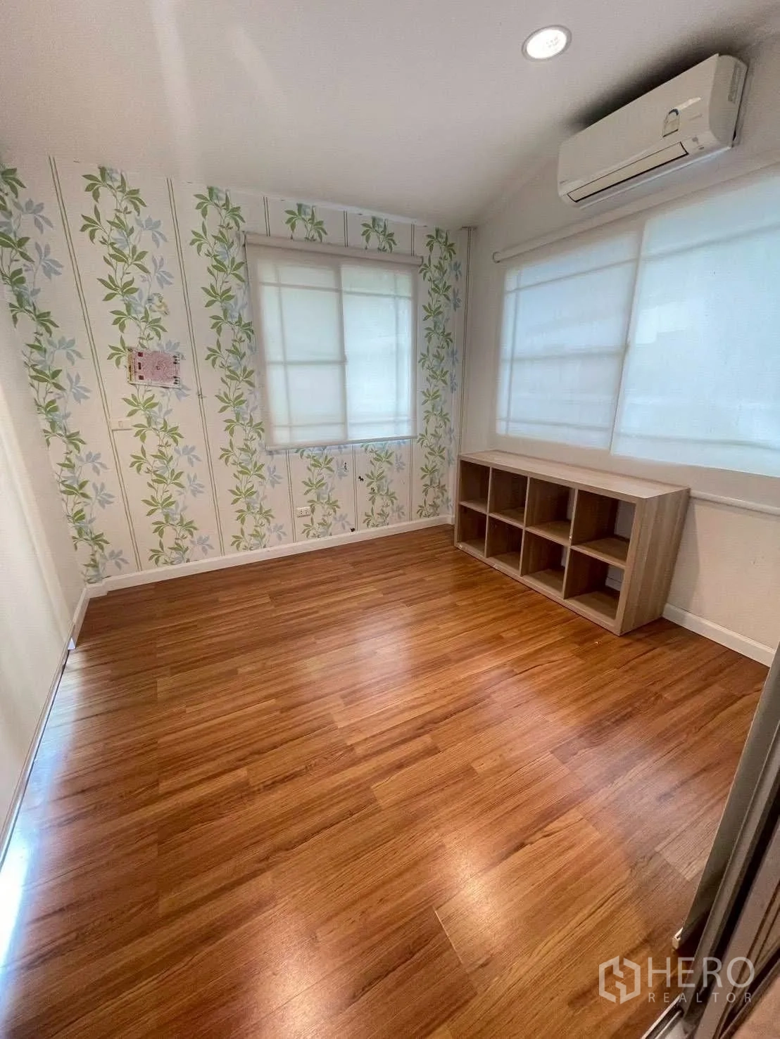 Detached House for rent or sale in Mueang Samut Prakan, Samut Prakan - Spare room with floral wallpaper, wood flooring, windows with blinds and wall-mounted air conditioner.