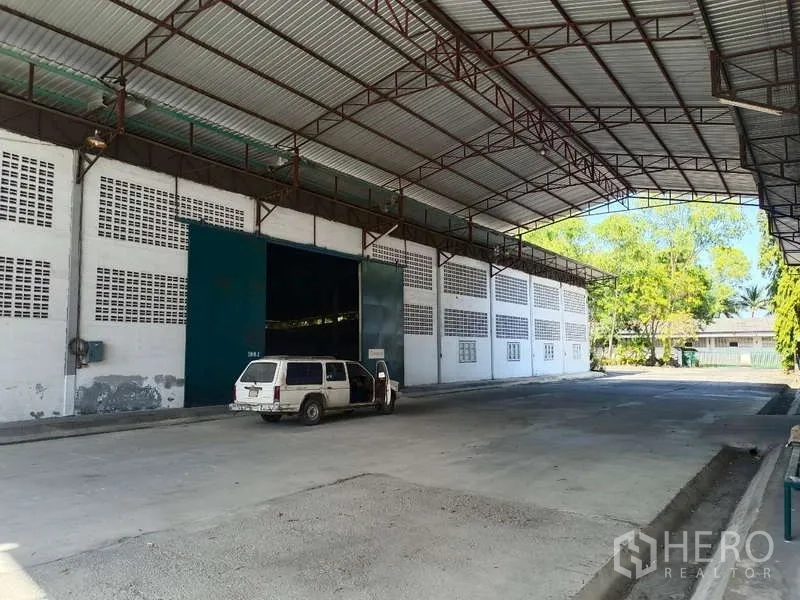Warehouse for rent in Mueang Rayong, Rayong - Covered loading bay with a high canopy at the warehouse entrance and a parked vehicle.