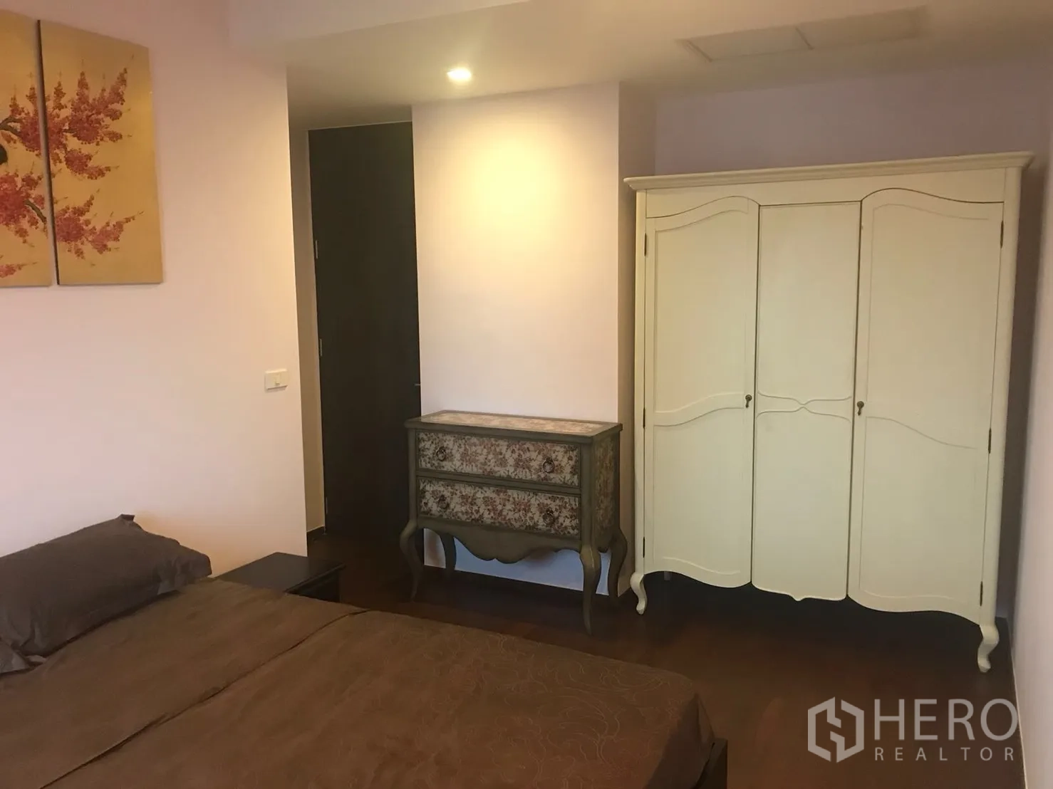 Condominium for rent in Khlong Toei, Bangkok - Bedroom interior with wardrobe and vintage dresser on wooden flooring.