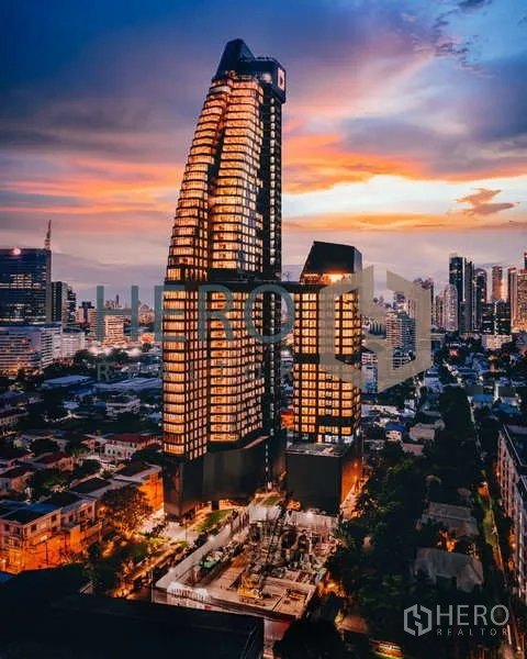 Condominium for rent - Exterior of Ideo Q Sukhumvit 36 towers at sunset overlooking Bangkok skyline.