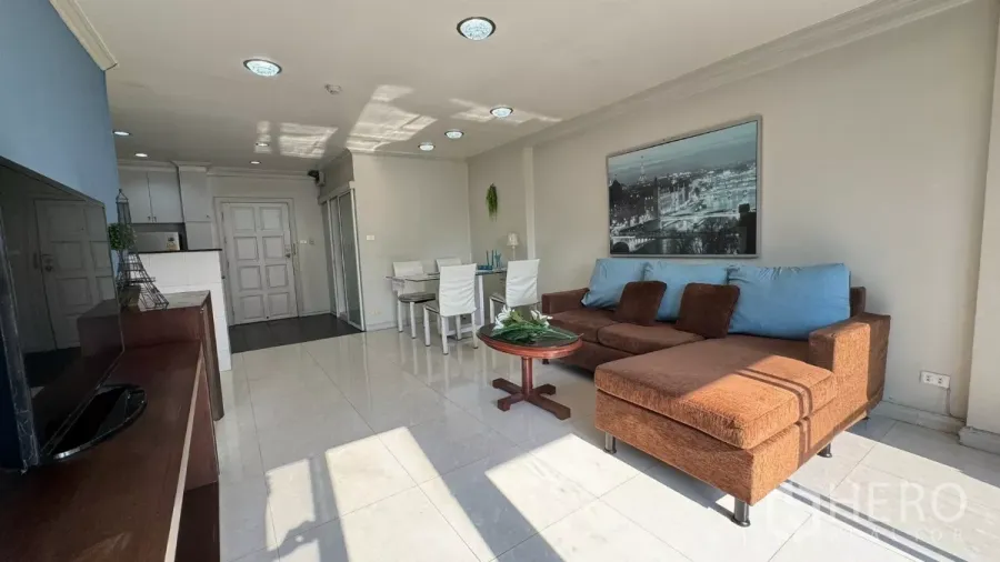 Condominium for rent in Khlong Toei, Bangkok - Bright open-plan living room with L-shaped sofa, dining set and white tile floors.