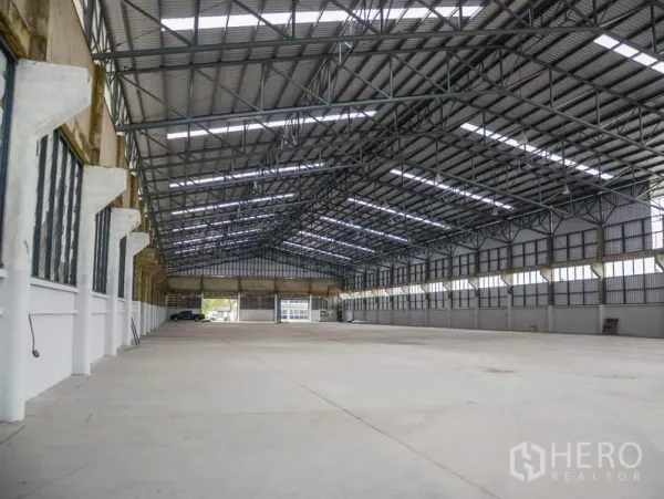 Factory for rent in Pathum Thani - Vast warehouse hall featuring a steel truss roof, skylights, and open loading access.