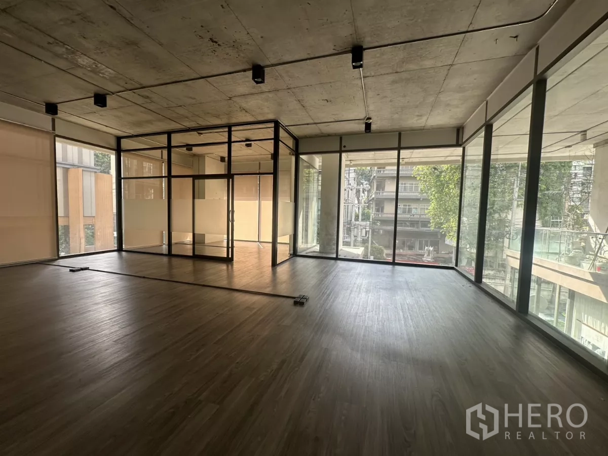 Retail Space for rent - Corner retail space with panoramic glazing on two sides, framed by city views and a balcony edge.