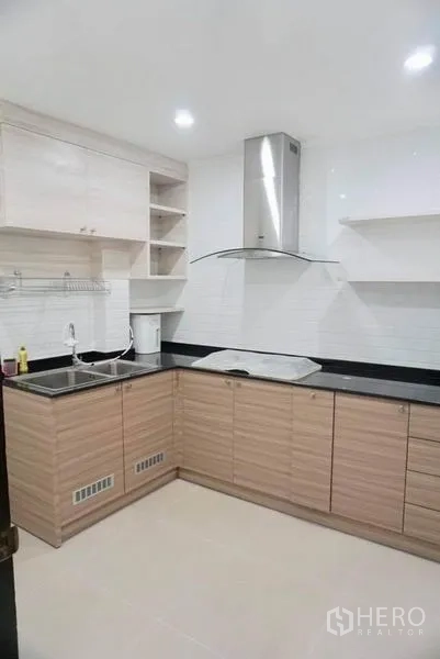 Detached House for rent in Suan Luang, Bangkok - Modern L-shaped kitchen with wood cabinetry, black countertops, sink and range hood.