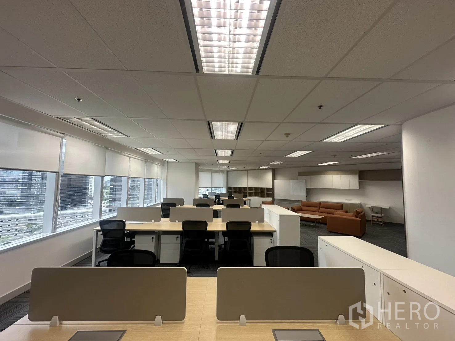 Office Space for rent in Pathum Wan, Bangkok - Open workspace with bench desks, storage pedestals, and full-length windows.