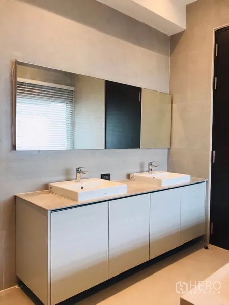 Townhouse for rent or sale in Khlong Toei, Bangkok - Bathroom featuring a double-sink vanity and wide mirror cabinet.