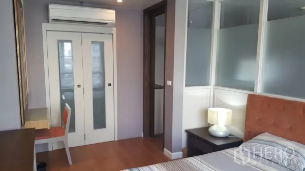 Condominium for rent in Khlong Toei, Bangkok - Bedroom view with sliding glass doors, study nook and air conditioner above.