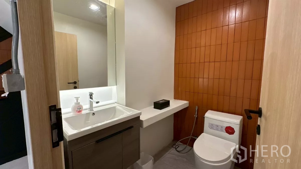 带办公室的家 出租在Watthana, Bangkok - 客用卫浴，带洗手台与坐便，橙色砖墙点缀。