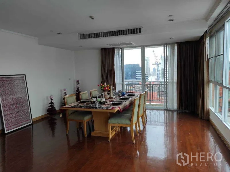 Condominium for rent in Khlong Toei, Bangkok - Dining area with city-view balcony and wide windows flooding the room with light.