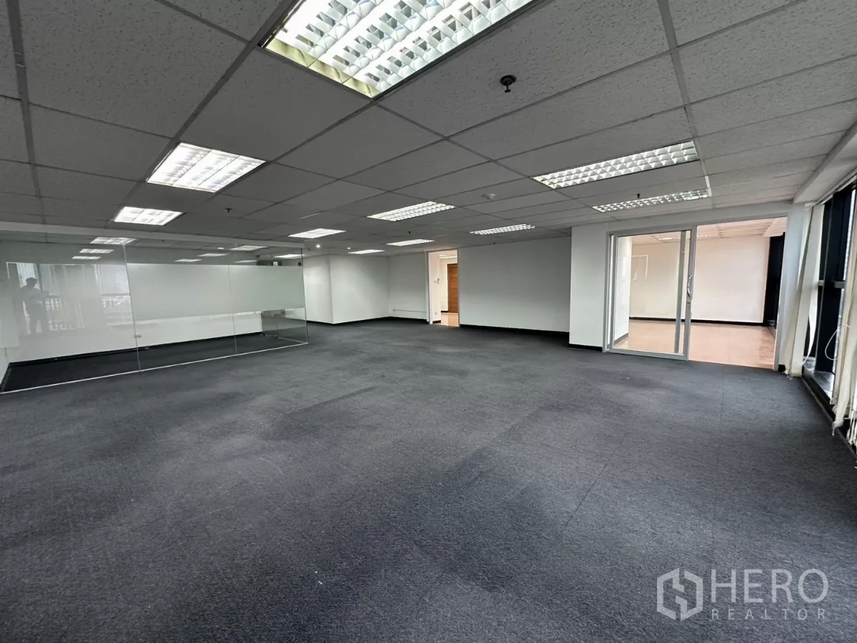 Office Space for rent in Watthana, Bangkok - Open office showing a glass meeting room, floor-to-ceiling windows, and access to a tiled auxiliary area.