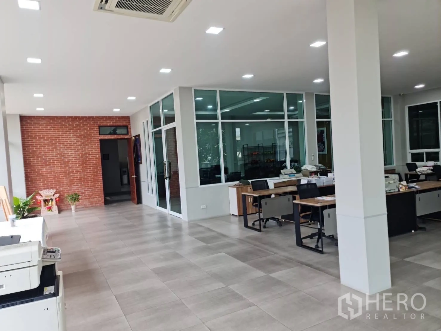 Factory for sale in Krathum Baen, Samut Sakhon - Office corridor with brick feature wall and enclosed glass rooms.