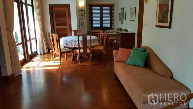 Townhouse for rent in Khlong Toei, Bangkok - Open-plan living and dining area with wood floors and balcony access.