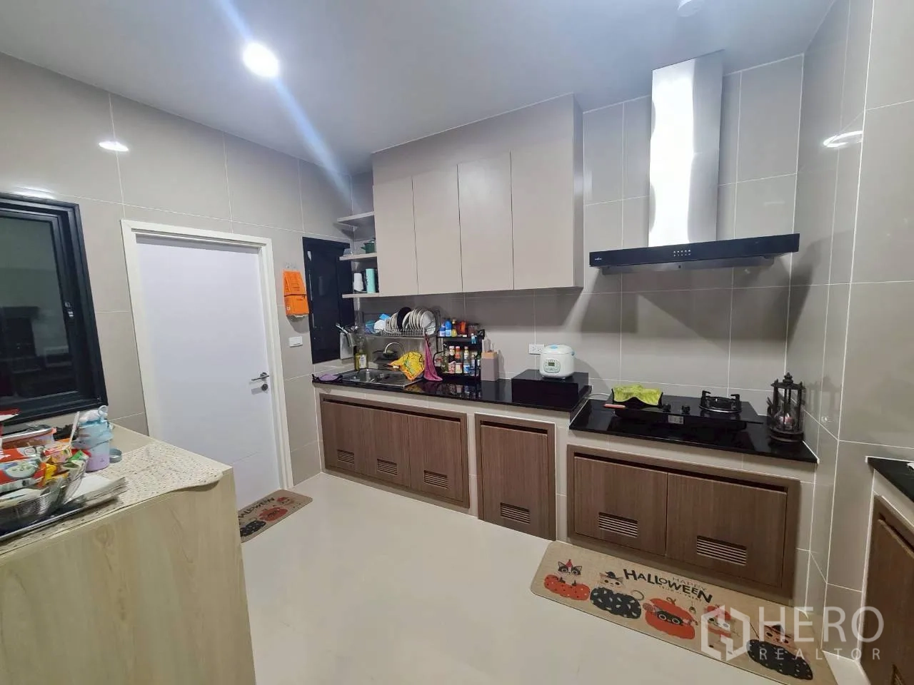 Detached House for rent or sale in Lam Luk Ka, Pathum Thani - Fitted Thai kitchen with upper cabinets, gas hob, range hood and tiled walls.