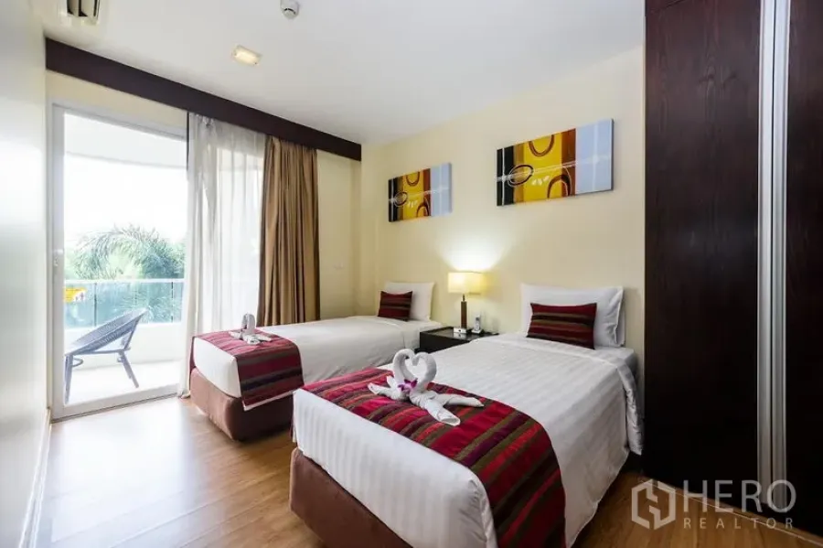 Condominium for rent in Khlong Toei, Bangkok - Twin bedroom with sliding glass door to a balcony, two single beds and a greenery view.