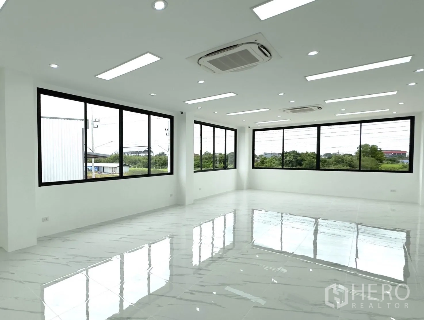Factory for rent or sale in Bang Yai, Nonthaburi - Corner office with full-height windows, multiple AC cassettes and reflective tile floors.