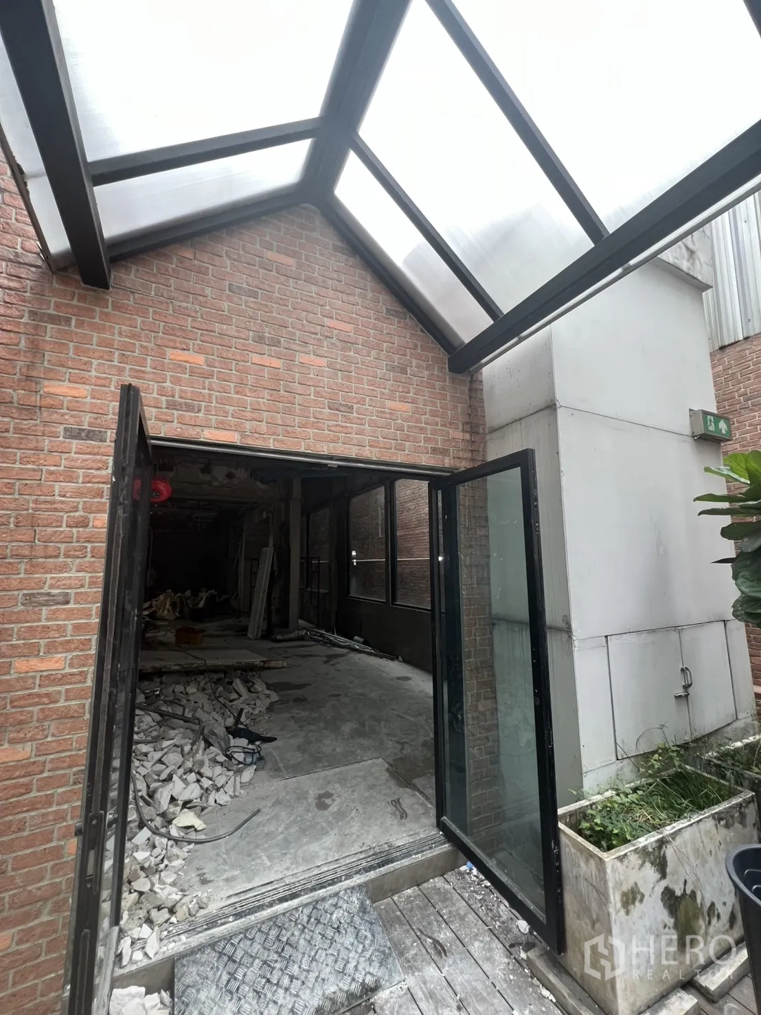 店屋 出租在Bang Rak, Bangkok - 玻璃门通向施工区域，半透明顶棚与建筑废料