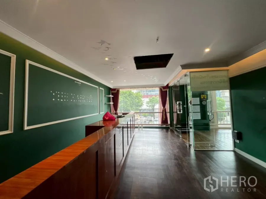 สำนักงาน ให้เช่าในWatthana, Bangkok - โถงต้อนรับพื้นไม้สีเข้ม ผนังสีเขียว หน้าต่างบานใหญ่และประตูกระจก เหมาะใช้ออฟฟิศหรือร้านค้า
