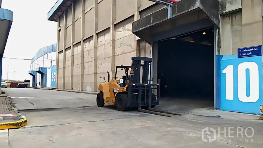 Factory for rent in Khlong Toei, Bangkok - Forklift approaching a wide factory loading bay with a high-clearance entrance and paved driveway.